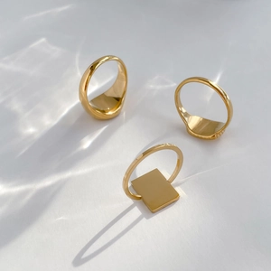 Three-piece gold geometric ring set including oval and rectangular signet styles