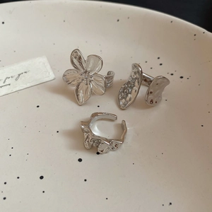 Detailed view of three silver irregular floral and lava style rings on a ceramic plate