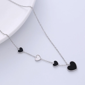 Silver stainless steel necklace with multi-size black and white heart pendants on light background