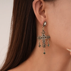 Gros plan de boucles d'oreilles croix vintage avec perles et strass portées par un mannequin