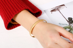 Detailed macro view of the gold frosted texture on the stainless steel open bangle