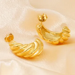 Elegant gold-plated croissant-style twisted C-shape earrings on champagne silk background