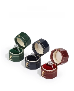 Three octagonal vintage jewelry boxes in emerald, navy, and wine red with gold trim