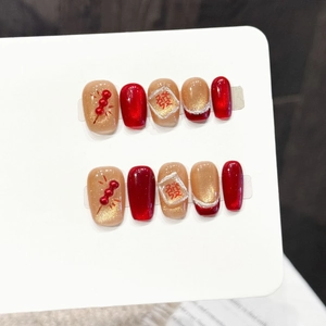 Detalle de uñas postizas rojas y doradas con tanghulu 3D y el carácter chino 'Fa'