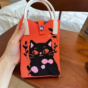 Détail du mini sac tricoté orange avec motif chat noir et poignée en cuir élégante