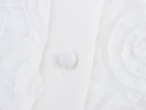 Detailed macro shot of white lace texture and matching fabric button on sleeveless top