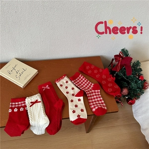 Five pairs of festive Christmas red cotton crew socks with diverse patterns on wooden surface