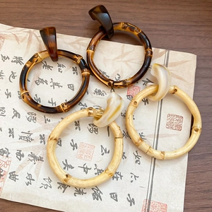 Detailed close-up of brown resin bamboo hoops on vintage calligraphy paper background