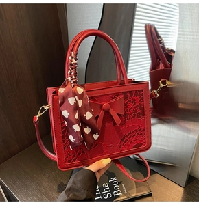 Detailed red lace embroidery handbag with decorative silk scarf on handle and bow detail