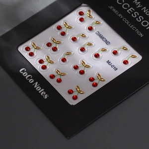 3D cherry nail art stickers with red rhinestones and gold leaf details on black card
