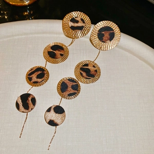 Close-up of leopard print drop earrings with gold-tone metal circles and tassel detail