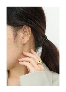 Close-up of elegant gold-plated small hoop earrings and twist ear cuff on female model