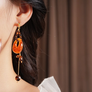 Close-up of model wearing tiger eye resin round earrings with hanging metal chain