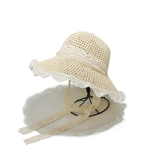 Women's beige crochet straw hat with lace trim and long ribbons on a metal stand
