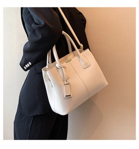 Close-up of ivory pebble leather handbag featuring gold accents and textured finish