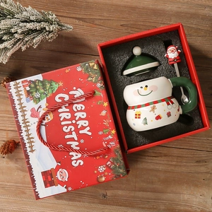Christmas ceramic snowman mug set with lid, spoon and red gift box on festive wooden background