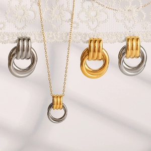 Flat lay of textured metal hoop jewelry set with necklace on marble and lace background