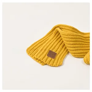 Detailed macro view of yellow chunky knit children scarf with embossed faux leather label