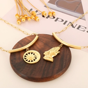 Détail de pendentifs soleil et main en acier titane doré sur support en bois