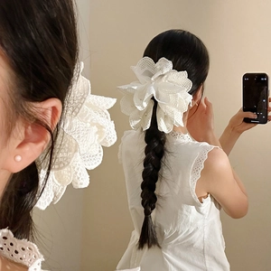 Elegant white lace flower hair claw with pearls shown on a ponytail with mirror reflection