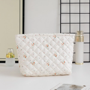 Close-up of quilted floral cosmetic bag on table with skincare items and accessories