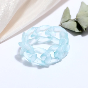 Detail of light blue matte resin chain link ring on silk and dried leaf background
