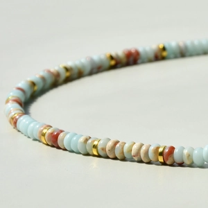 Macro detail of light blue and marble texture beads with gold metal spacers necklace