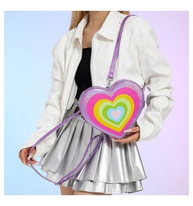 Detail of purple sequin heart-shaped crossbody bag with rainbow heart layers on model