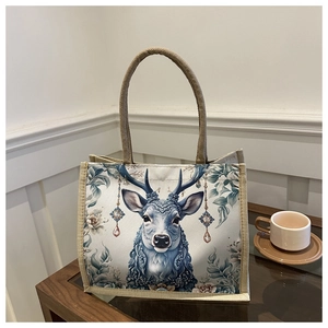 Detail of linen tote bag featuring a majestic deer illustration on dark wood surface