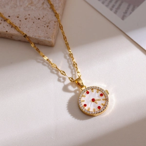 Close-up of gold clock pendant with mother-of-pearl dial and red zircon markers