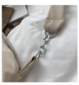 Detail of the shiny silver metal chain link on a light apricot canvas shoulder bag