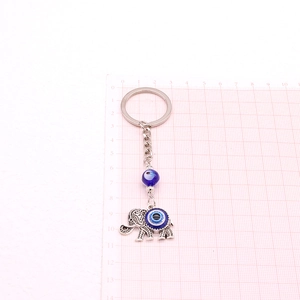 Retro elephant keychain with blue evil eye bead shown on a scale for size reference