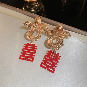 Detailed view of gold flower earrings with red Double Happiness tassels for bridal jewelry