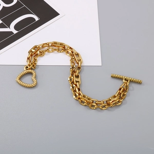 Detail of gold double-layer marine link bracelet with heart pendant and toggle clasp