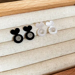 Herzförmige Ohrringverschlüsse aus Acryl in Schwarz und Perlweiß auf Samttablett