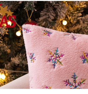 Close-up of pink plush pillow cover with colorful sequined snowflake embroidery