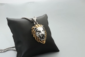 Vintage lion head pendant necklace with gold mane and silver face on display pillow