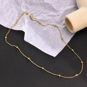 Close-up of golden beaded stainless steel necklace with heart charm and lobster clasp
