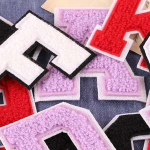 Colorful chenille letter patches with towel embroidery texture on blue denim background