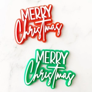 Close-up of 3D acrylic Merry Christmas cake toppers in festive red and green colors