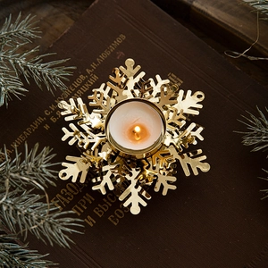 Golden snowflake metal candle holder on vintage book with pine needles Christmas decor