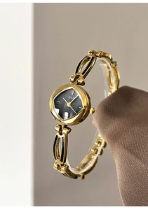 Detail of vintage gold bracelet watch featuring a geometric black dial and hollowed metal band