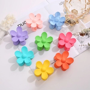 Matte flower hair claws in multiple candy colors arranged on a white table with props
