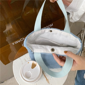 Detail of light blue corduroy tote bag featuring snap button closure and inner pocket