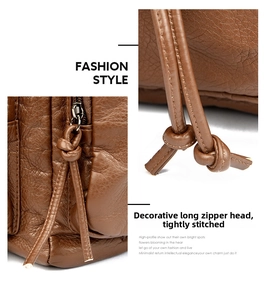 Macro detail of brown leather bag showing long zipper pulls and precise stitching