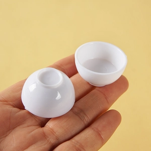 Miniature white plastic bowls for dollhouse scenes shown held in hand for scale