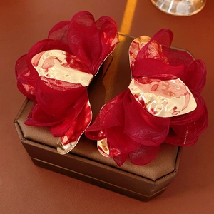 Close-up of dark red chiffon flower earrings with textured gold metal center details