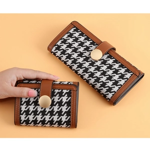 Detail of houndstooth wallet with brown leather trim and golden snap button closure