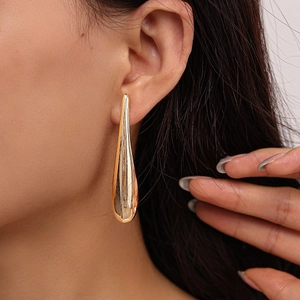 Close-up of elegant gold teardrop earrings worn by a model to show texture and length