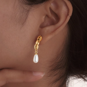 Vintage stainless steel chain earrings with white teardrop pearls on a female model